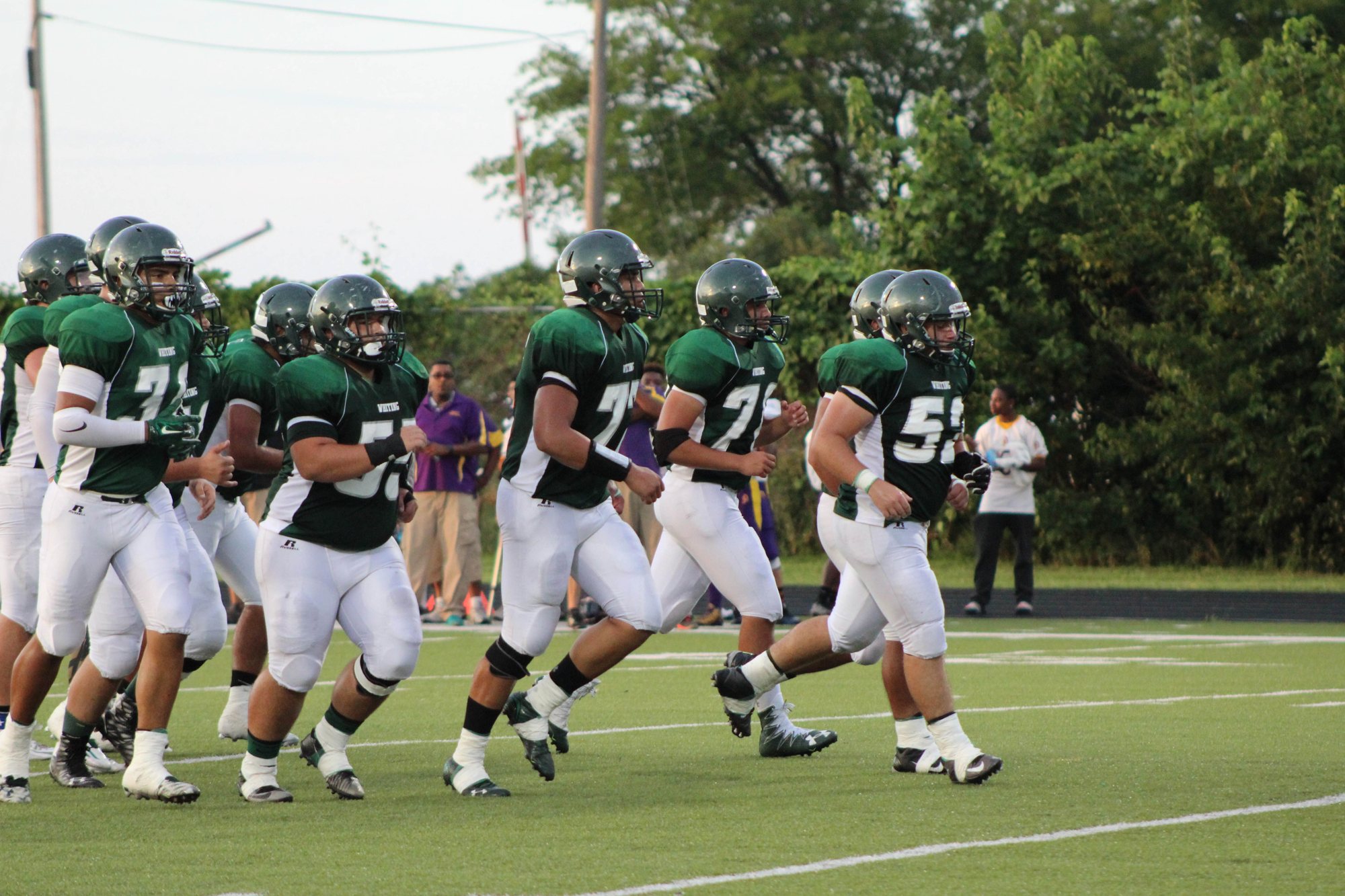 Whiting players in green jerseys jogging onto the field during the 2016 season.